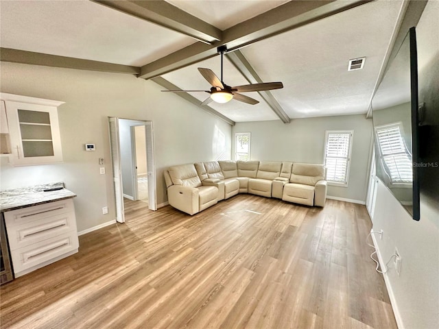 unfurnished living room featuring lofted ceiling with beams, light hardwood / wood-style floors, a textured ceiling, and ceiling fan