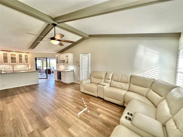 unfurnished living room with vaulted ceiling with beams, ceiling fan, sink, and light wood-type flooring