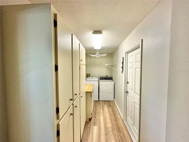 laundry area featuring cabinets, a textured ceiling, light wood-type flooring, and separate washer and dryer