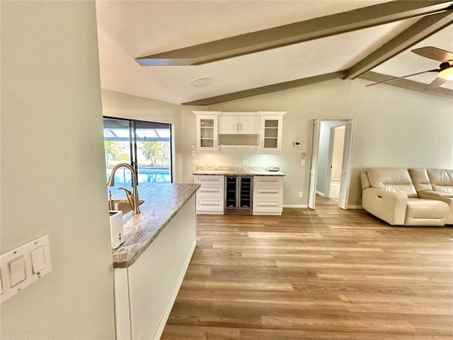 kitchen featuring white cabinetry, ceiling fan, vaulted ceiling with beams, wine cooler, and light hardwood / wood-style flooring