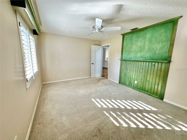 empty room with ceiling fan, carpet floors, and a textured ceiling