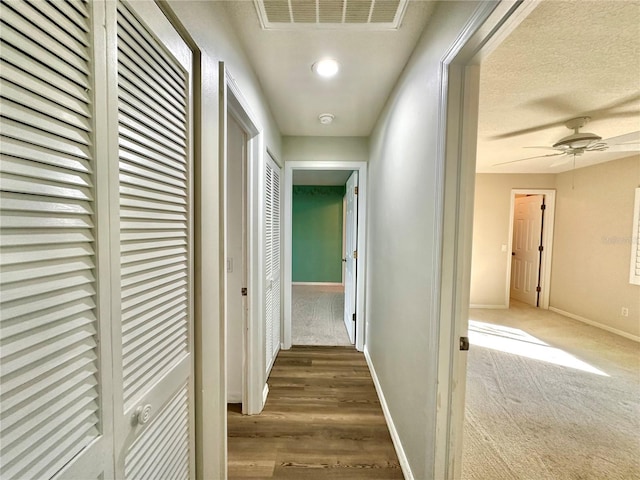 hallway with carpet flooring and a textured ceiling