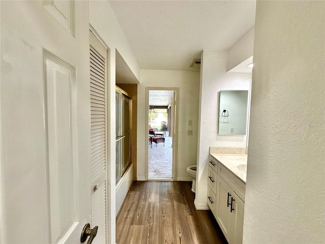 bathroom with vanity, hardwood / wood-style flooring, toilet, a textured ceiling, and a shower with shower door