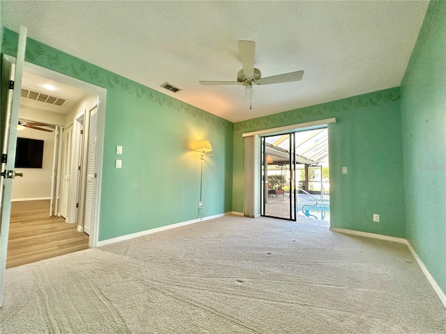 spare room featuring ceiling fan, light colored carpet, and a textured ceiling