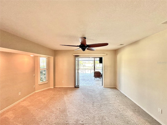 carpeted empty room with ceiling fan and a textured ceiling