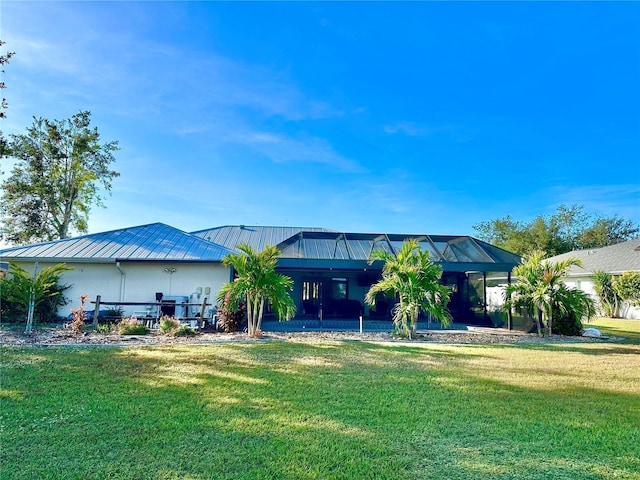 back of house featuring a lanai and a yard