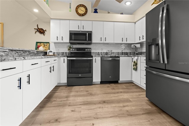 kitchen with decorative backsplash, white cabinetry, stainless steel appliances, and lofted ceiling