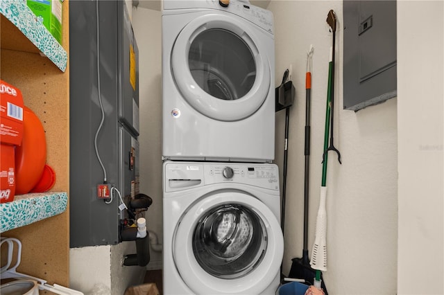 clothes washing area with electric panel and stacked washer and clothes dryer