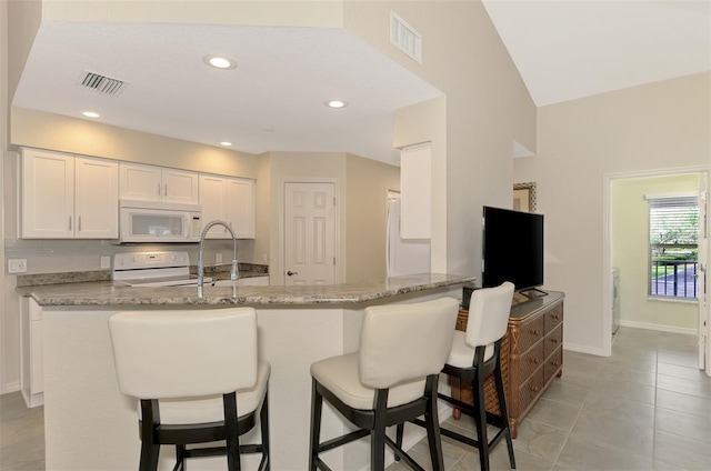 kitchen featuring kitchen peninsula, stove, light tile patterned floors, stone countertops, and white cabinets