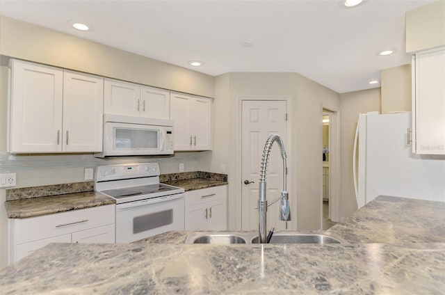 kitchen with white appliances, white cabinetry, dark stone counters, and sink