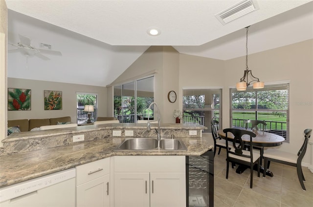 kitchen featuring sink, pendant lighting, dishwasher, white cabinets, and lofted ceiling