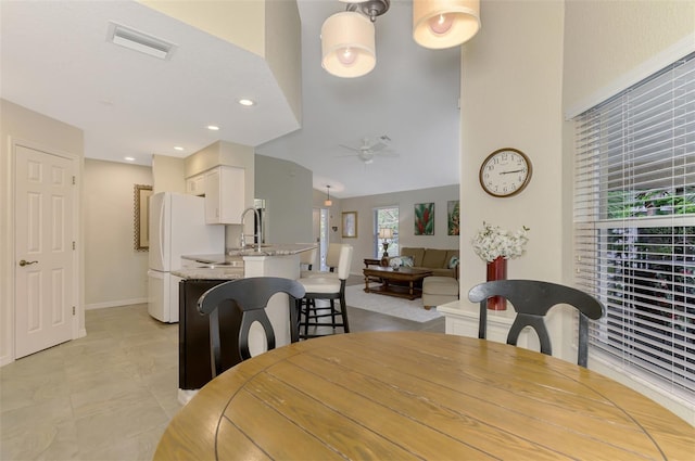 dining area featuring ceiling fan, sink, and vaulted ceiling