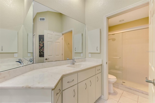 bathroom featuring tile patterned flooring, a tile shower, vanity, and toilet