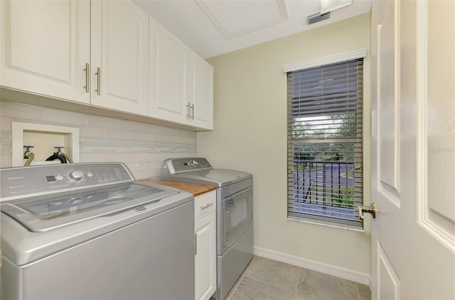 washroom featuring cabinets, washer and clothes dryer, and light tile patterned flooring