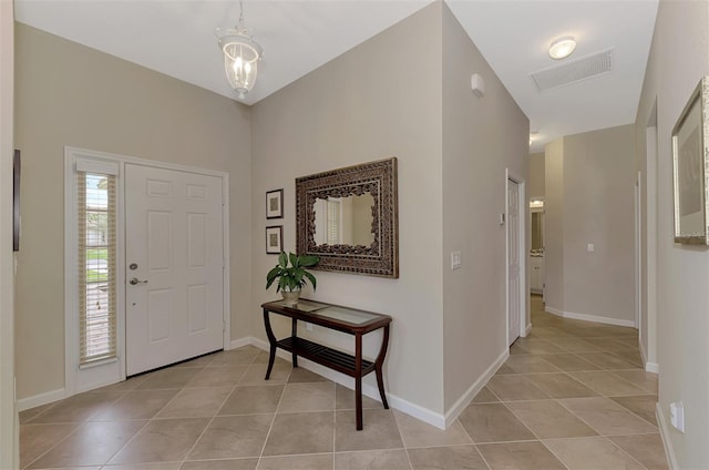 tiled entrance foyer featuring an inviting chandelier