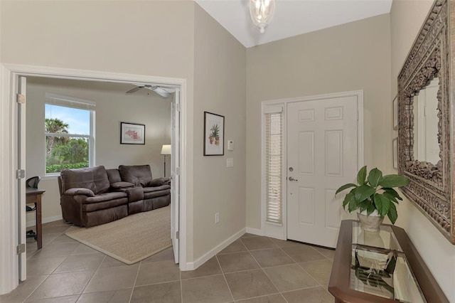 entrance foyer featuring light tile patterned floors, ceiling fan, and a high ceiling