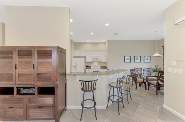 kitchen with light stone countertops, white appliances, light tile patterned floors, white cabinetry, and hanging light fixtures