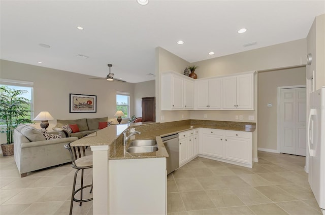 kitchen with a kitchen bar, kitchen peninsula, sink, dishwasher, and white cabinetry