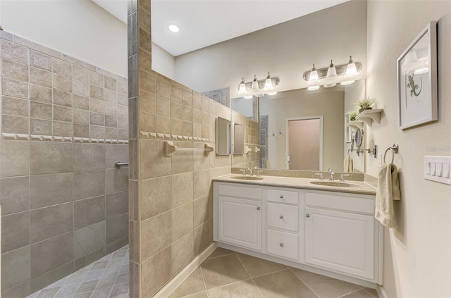 bathroom with tile patterned flooring, a tile shower, and vanity