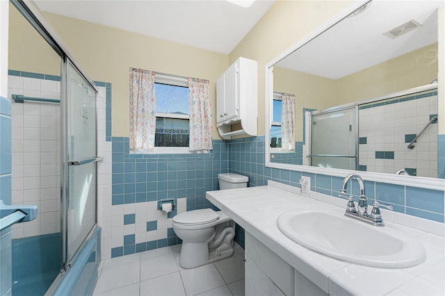 bathroom featuring tile patterned flooring, toilet, vanity, visible vents, and tile walls