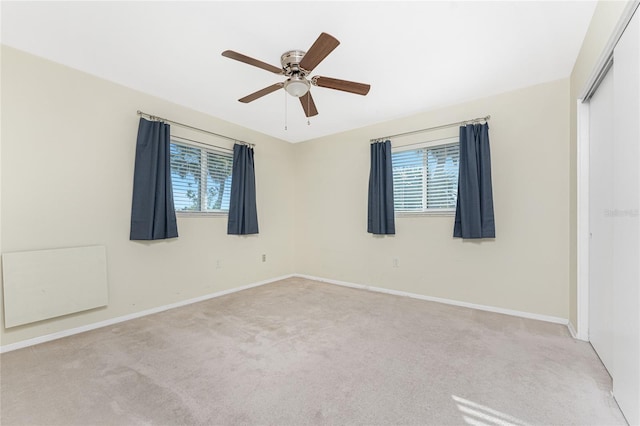 unfurnished bedroom with light carpet, a closet, a ceiling fan, and baseboards