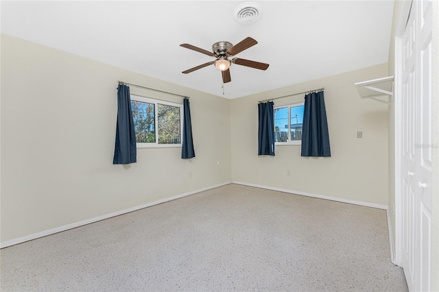 spare room with ceiling fan, visible vents, and baseboards