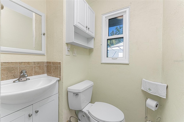 half bath with a textured wall, vanity, and toilet