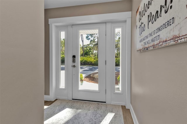 doorway featuring light wood-style flooring and baseboards