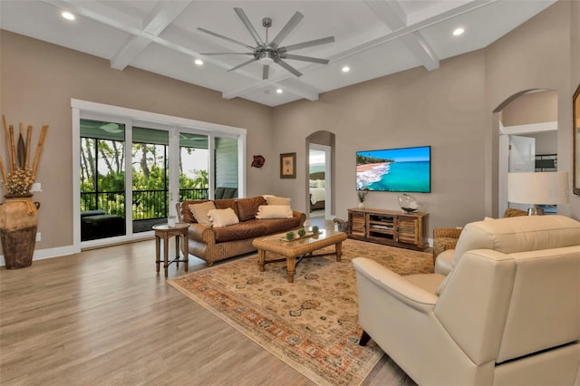 living room featuring arched walkways, coffered ceiling, and wood finished floors