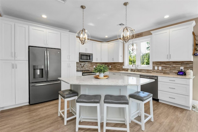 kitchen with appliances with stainless steel finishes, a kitchen island, and white cabinets