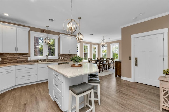 kitchen featuring visible vents, white cabinets, a notable chandelier, and a center island