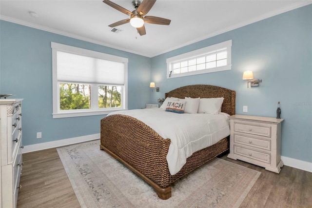 bedroom with visible vents, crown molding, baseboards, and wood finished floors