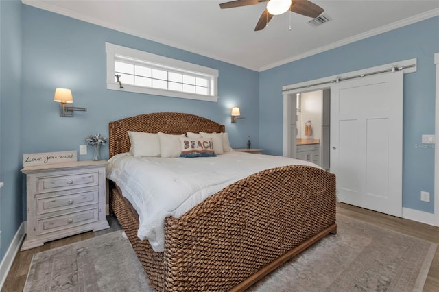 bedroom featuring a barn door, visible vents, baseboards, light wood finished floors, and crown molding