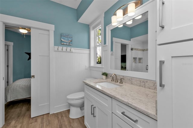 full bathroom featuring a stall shower, toilet, a wainscoted wall, wood finished floors, and vanity