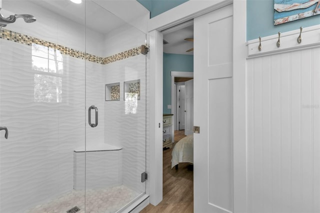 full bathroom with a stall shower, ensuite bath, wood finished floors, and a wainscoted wall