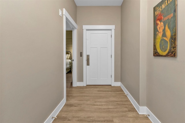 hall with light wood-type flooring and baseboards