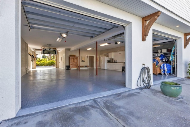 garage featuring driveway and white fridge with ice dispenser