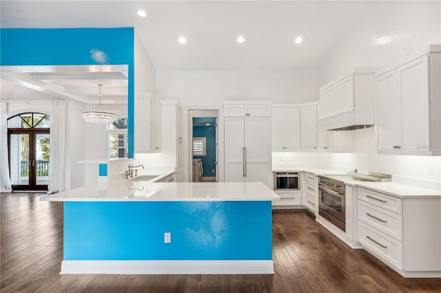 kitchen with dark wood-type flooring, sink, white cabinetry, appliances with stainless steel finishes, and kitchen peninsula