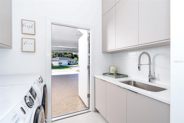 washroom with cabinets, independent washer and dryer, and sink