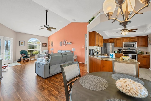 dining area featuring a raised ceiling, hardwood / wood-style floors, ceiling fan with notable chandelier, and lofted ceiling