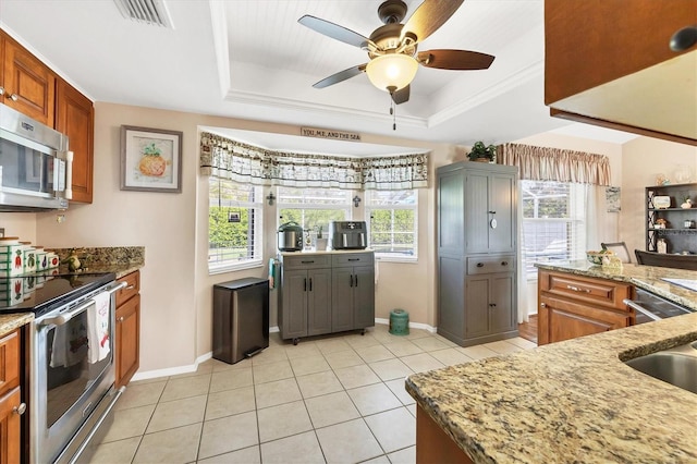 kitchen featuring light tile patterned floors, a raised ceiling, light stone countertops, and appliances with stainless steel finishes