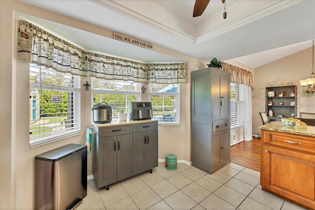 kitchen featuring gray cabinets, a healthy amount of sunlight, light tile patterned flooring, and crown molding