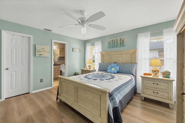 bedroom featuring a textured ceiling, ensuite bathroom, light hardwood / wood-style flooring, and ceiling fan