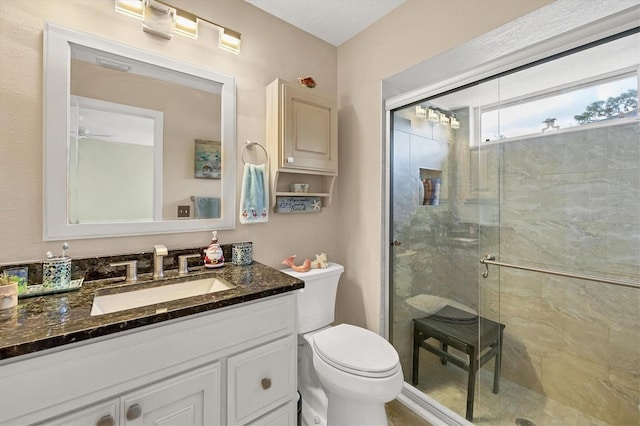 bathroom with vanity, toilet, ceiling fan, and a shower with shower door