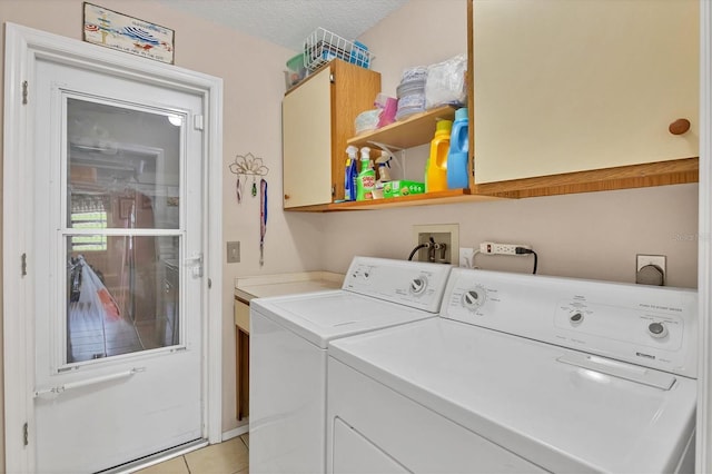 washroom featuring cabinets, light tile patterned floors, a textured ceiling, and washing machine and clothes dryer