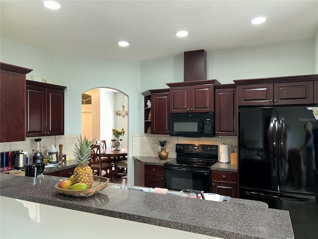 kitchen with kitchen peninsula, a kitchen bar, tasteful backsplash, sink, and black appliances