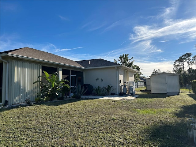 back of property featuring a lawn and a storage unit