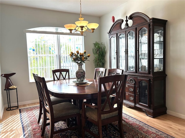 dining space with light hardwood / wood-style floors and a notable chandelier