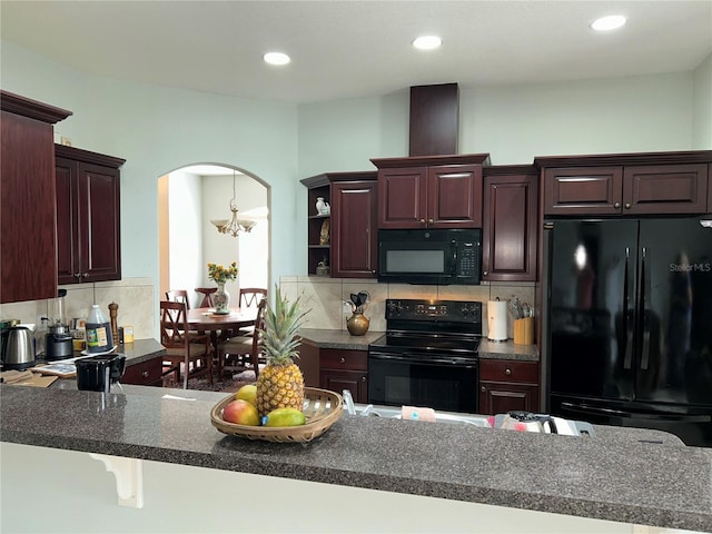 kitchen featuring an inviting chandelier, a kitchen breakfast bar, tasteful backsplash, kitchen peninsula, and black appliances