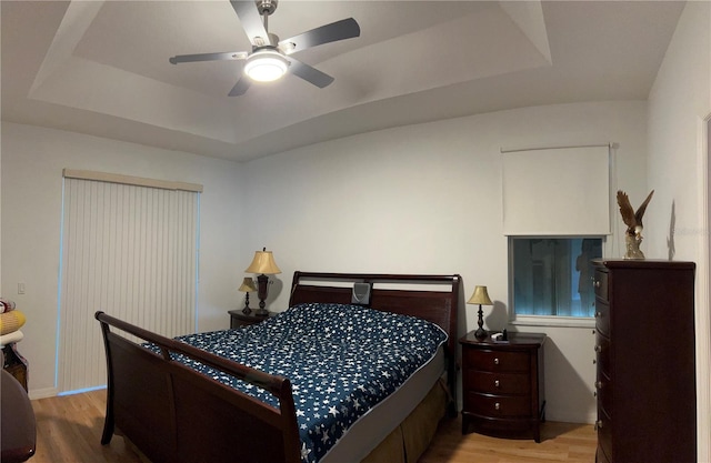 bedroom featuring a tray ceiling, ceiling fan, and wood-type flooring